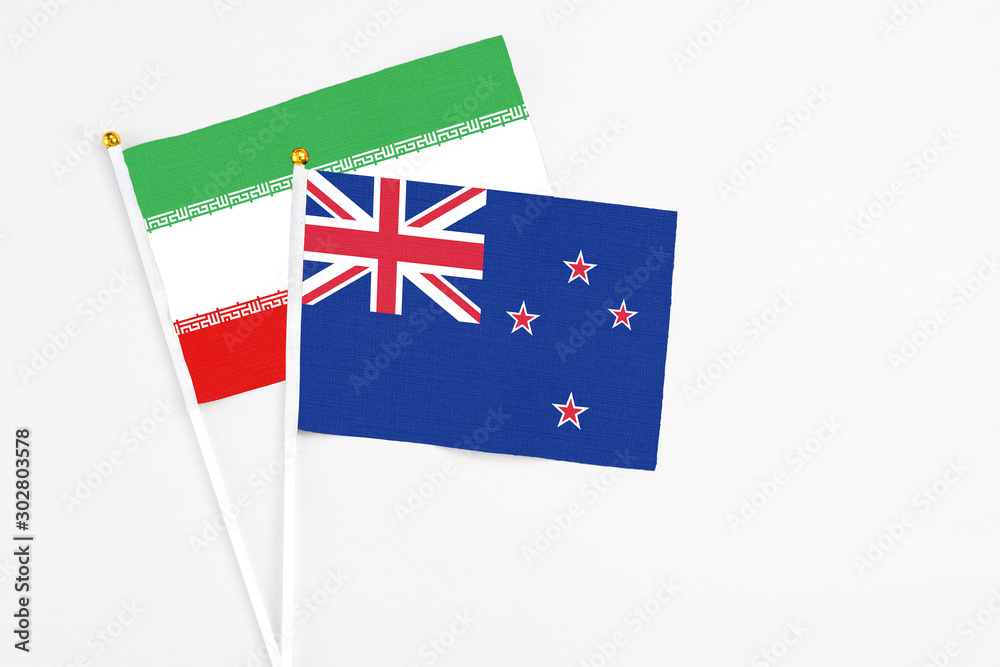 Fototapeta premium New Zealand and Iran stick flags on white background. High quality fabric, miniature national flag. Peaceful global concept.White floor for copy space.