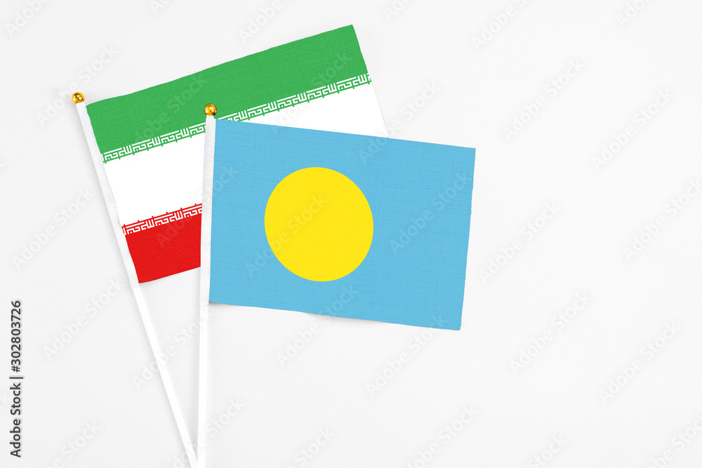 Palau and Iran stick flags on white background. High quality fabric, miniature national flag. Peaceful global concept.White floor for copy space. Palau and Iran stick flags on white background. High quality fabric, miniature national flag. Peaceful global concept.White floor for copy space.