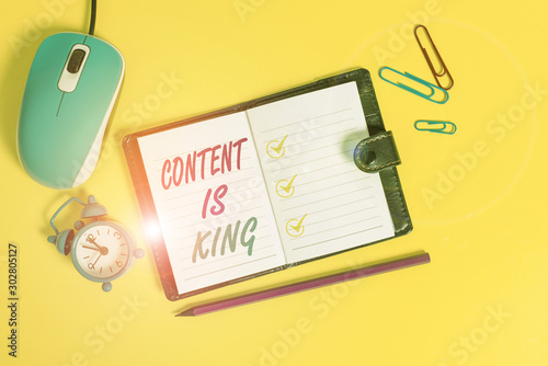 Word writing text Content Is King. Business photo showcasing Content is the heart of todays marketing strategies Locked diary sheets clips marker mouse alarm clock colored background