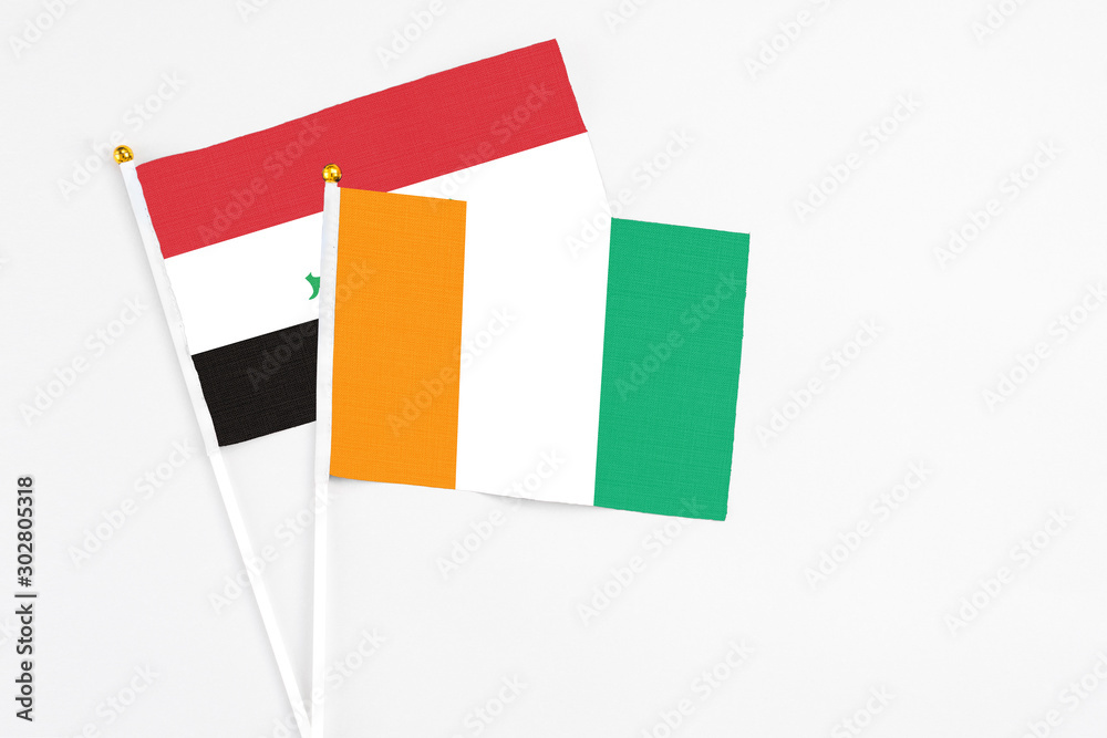 Cote D'Ivoire and Iraq stick flags on white background. High quality fabric, miniature national flag. Peaceful global concept.White floor for copy space. Cote D'Ivoire and Iraq stick flags on white background. High quality fabric, miniature national flag. Peaceful global concept.White floor for copy space.