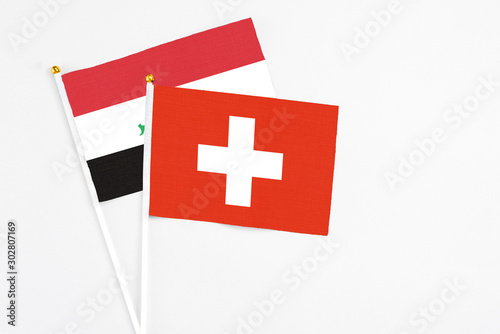 Switzerland and Iraq stick flags on white background. High quality fabric, miniature national flag. Peaceful global concept.White floor for copy space. photo