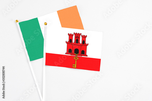 Gibraltar and Ireland stick flags on white background. High quality fabric, miniature national flag. Peaceful global concept.White floor for copy space photo