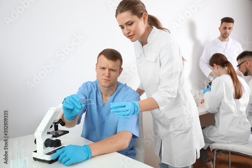 Medical students looking at test slide in laboratory