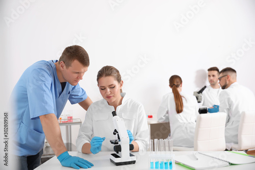Medical students working with microscope in modern laboratory