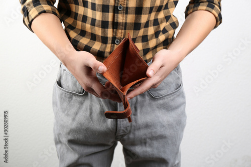 Man showing empty wallet on light background, closeup