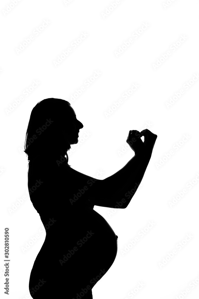 silhouette of a pregnant woman on a white background. The expectant mother shows the heart sign with her hands. The concept of a healthy lifestyle, IVF, expression of emotions, gestures. Copy space