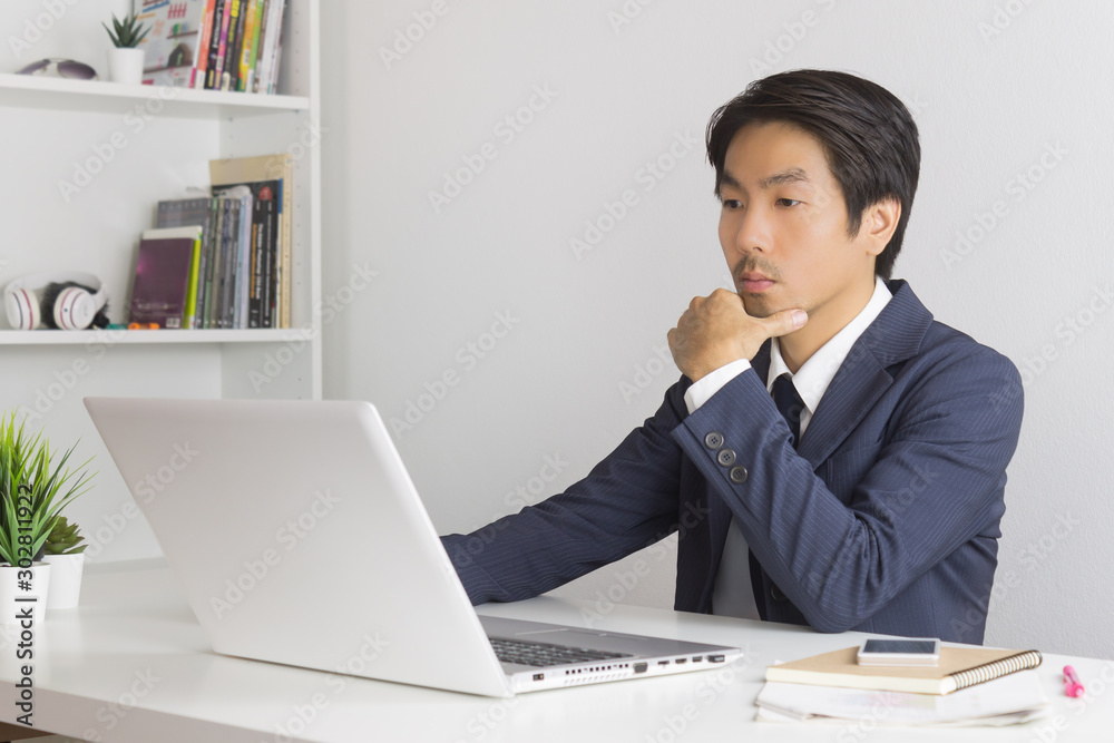 Asian Financial Advisor or Asian Consulting Businessman Thinking in front of Laptop Monitor Asian Financial Advisor or Asian Consulting Businessman Thinking in front of Laptop Monitor