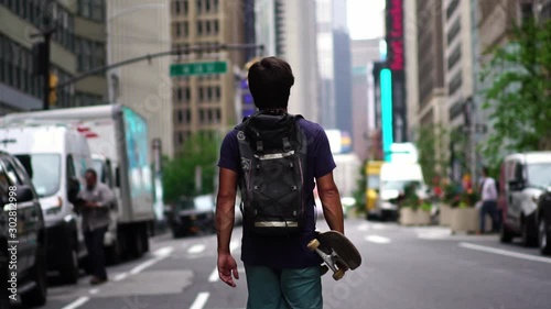 Young athletic male skateboarder confident man walking on New York street. Concept of urban healthy active lifestyle, adventure, american youth, hipster millennial in NYC.