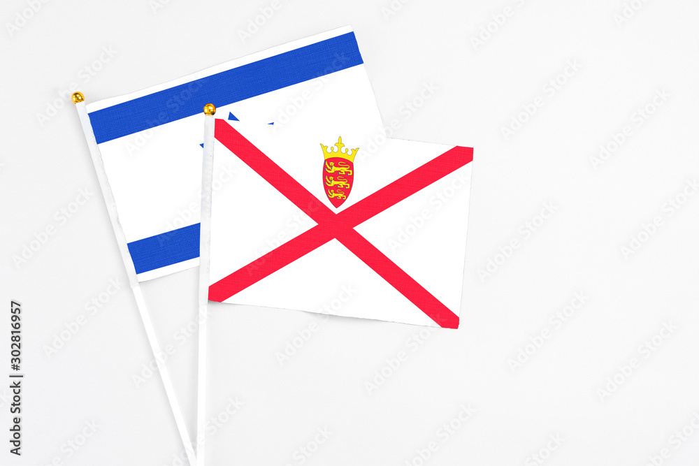 Fototapeta premium Jersey and Israel stick flags on white background. High quality fabric, miniature national flag. Peaceful global concept.White floor for copy space.
