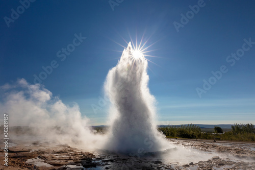 Strokkur Geyser in the Geysir geothermal area along the Golden circle of Iceland. An explosion of boiling water swallowing the sun