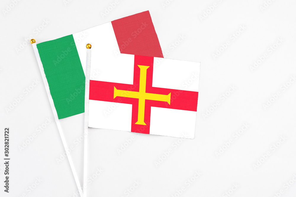 Guernsey and Italy stick flags on white background. High quality fabric, miniature national flag. Peaceful global concept.White floor for copy space.