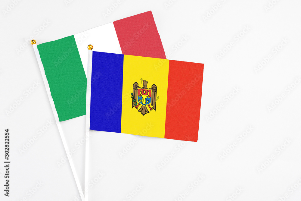 Fototapeta premium Moldova and Italy stick flags on white background. High quality fabric, miniature national flag. Peaceful global concept.White floor for copy space.