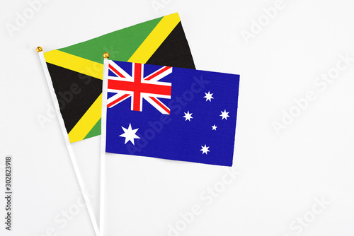 Australia and Jamaica stick flags on white background. High quality fabric, miniature national flag. Peaceful global concept.White floor for copy space.