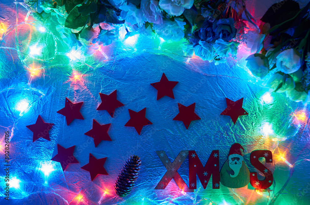 Red Christmas wooden stars with the inscription. With included garlands on a light background and a pine cone.