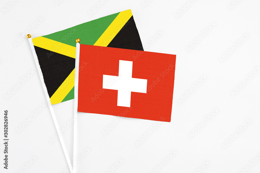 Switzerland and Jamaica stick flags on white background. High quality fabric, miniature national flag. Peaceful global concept.White floor for copy space.