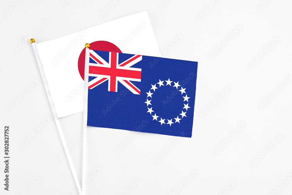 Fototapeta premium Cook Islands and Japan stick flags on white background. High quality fabric, miniature national flag. Peaceful global concept.White floor for copy space.