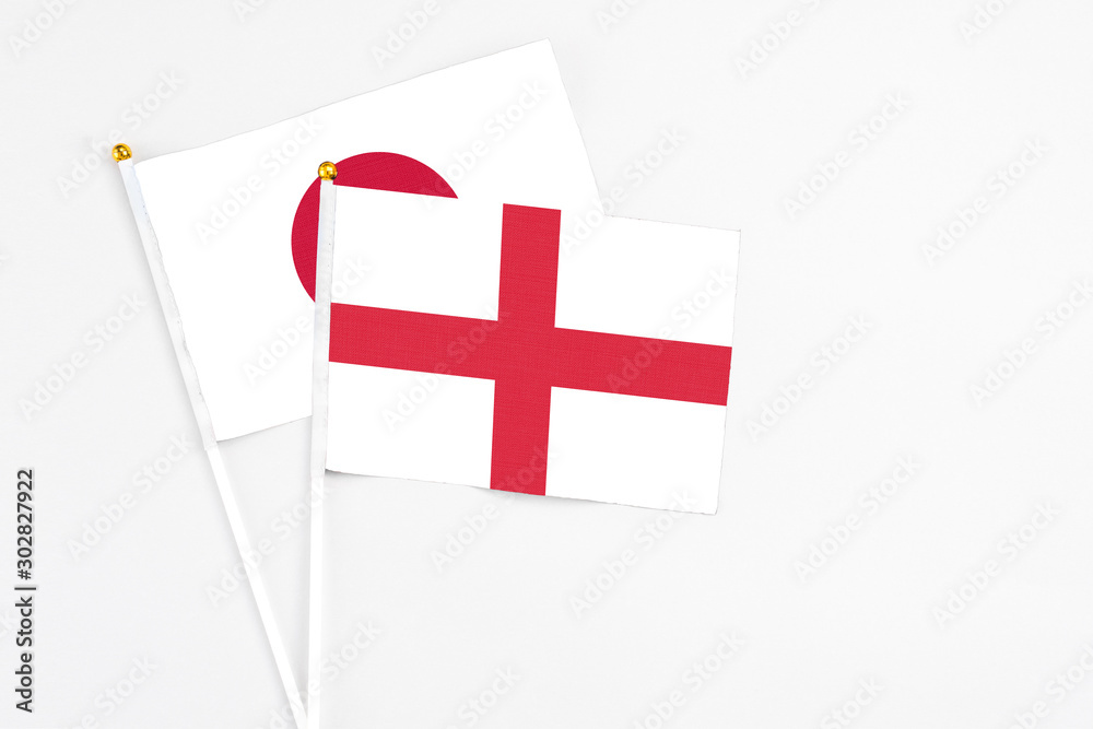England and Japan stick flags on white background. High quality fabric, miniature national flag. Peaceful global concept.White floor for copy space.