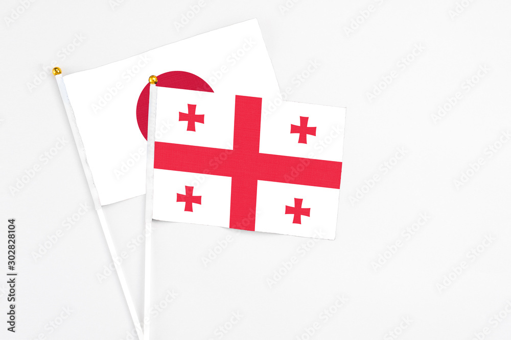 Georgia and Japan stick flags on white background. High quality fabric, miniature national flag. Peaceful global concept.White floor for copy space.