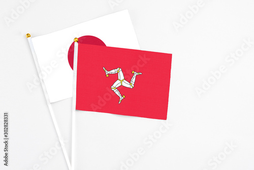 Isle Of Man and Japan stick flags on white background. High quality fabric, miniature national flag. Peaceful global concept.White floor for copy space.