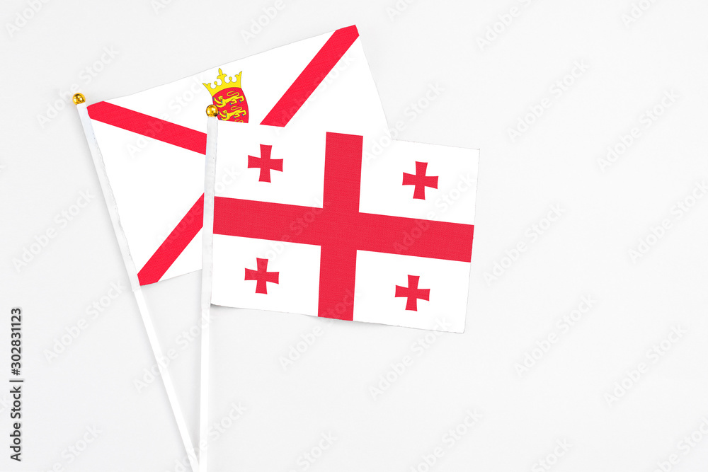 Georgia and Jersey stick flags on white background. High quality fabric, miniature national flag. Peaceful global concept.White floor for copy space.