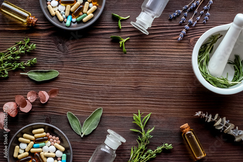 Apothecary of natural wellness and self-care. Herbs and medicine on dark wooden background top view frame copy space