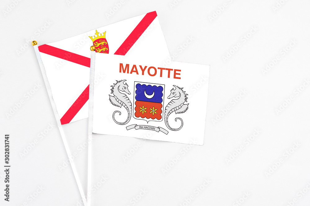 Mayotte and Jersey stick flags on white background. High quality fabric, miniature national flag. Peaceful global concept.White floor for copy space.