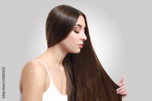 Beautiful woman with healthy long hair on light background