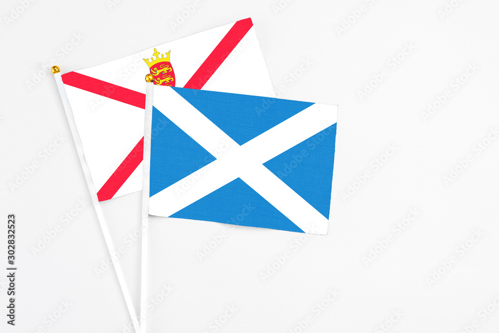 Scotland and Jersey stick flags on white background. High quality fabric, miniature national flag. Peaceful global concept.White floor for copy space. Scotland and Jersey stick flags on white background. High quality fabric, miniature national flag. Peaceful global concept.White floor for copy space.