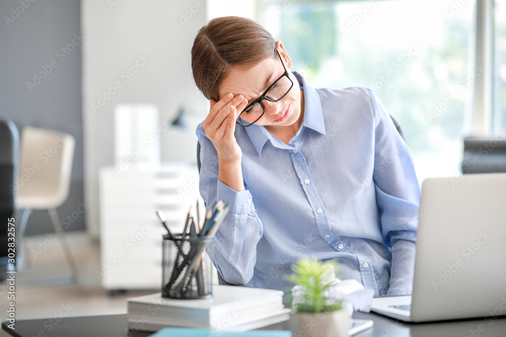 Young woman suffering from headache in office Young woman suffering from headache in office