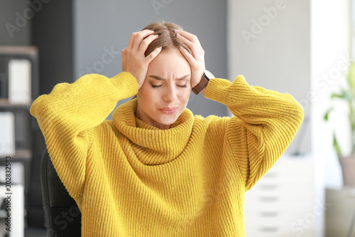 Young woman suffering from headache at home photo