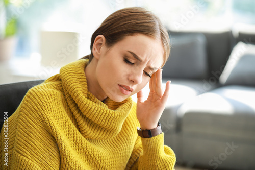 Young woman suffering from headache at home photo