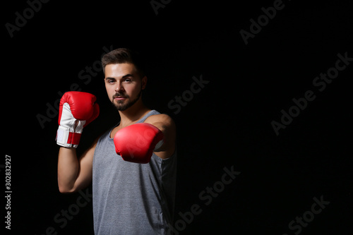 Sporty male boxer on dark b...
