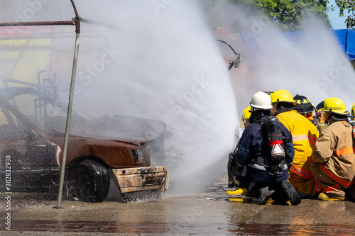 Brave firefighter using extinguisher and water from hose for fire fighting, Firefighter spraying high pressure water to fire, Firefighters fighting fire during training..