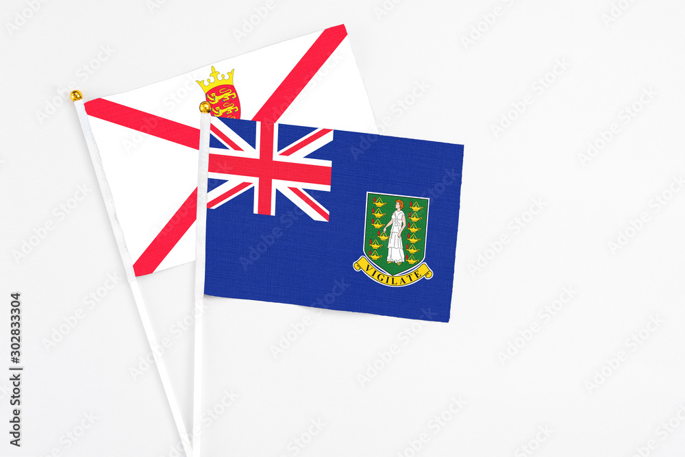 Fototapeta premium British Virgin Islands and Jersey stick flags on white background. High quality fabric, miniature national flag. Peaceful global concept.White floor for copy space.