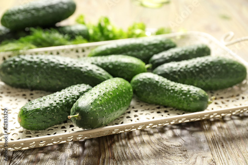 Tray with fresh cucumbers on wooden table