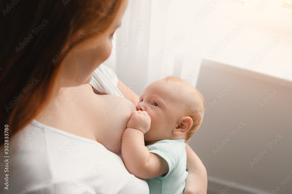 Young woman breastfeeding her baby at home Young woman breastfeeding her baby at home