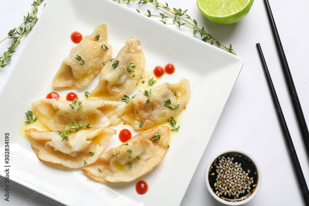 Plate with tasty Japanese gyoza and sauce on white background Plate with tasty Japanese gyoza and sauce on white background