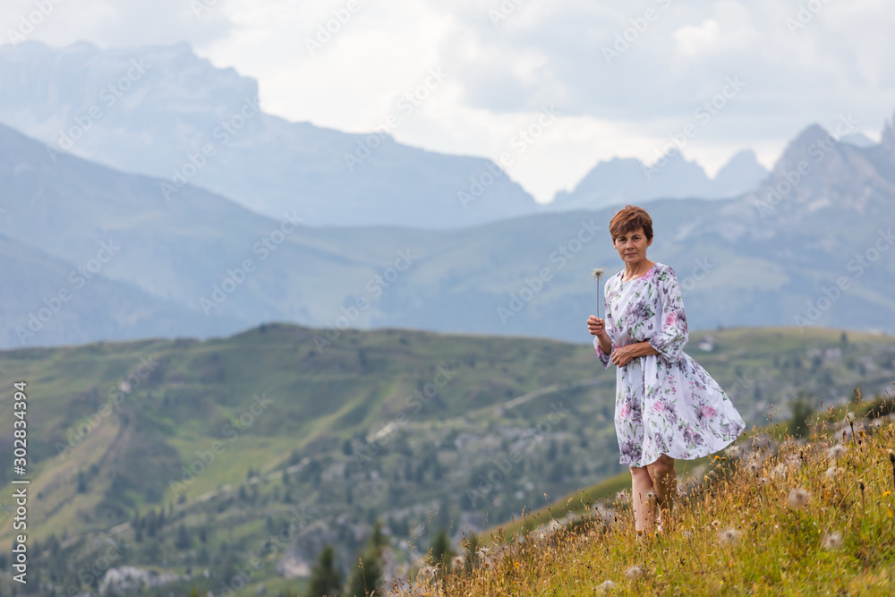 Girl in a dress on a background of mountains. Mountain valley of the Alps, Dolomites. Summer sunny day