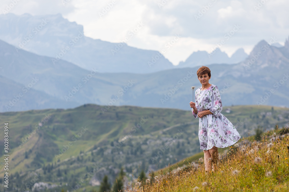 Girl in a dress on a background of mountains. Mountain valley of the Alps, Dolomites. Summer sunny day Girl in a dress on a background of mountains. Mountain valley of the Alps, Dolomites. Summer sunny day
