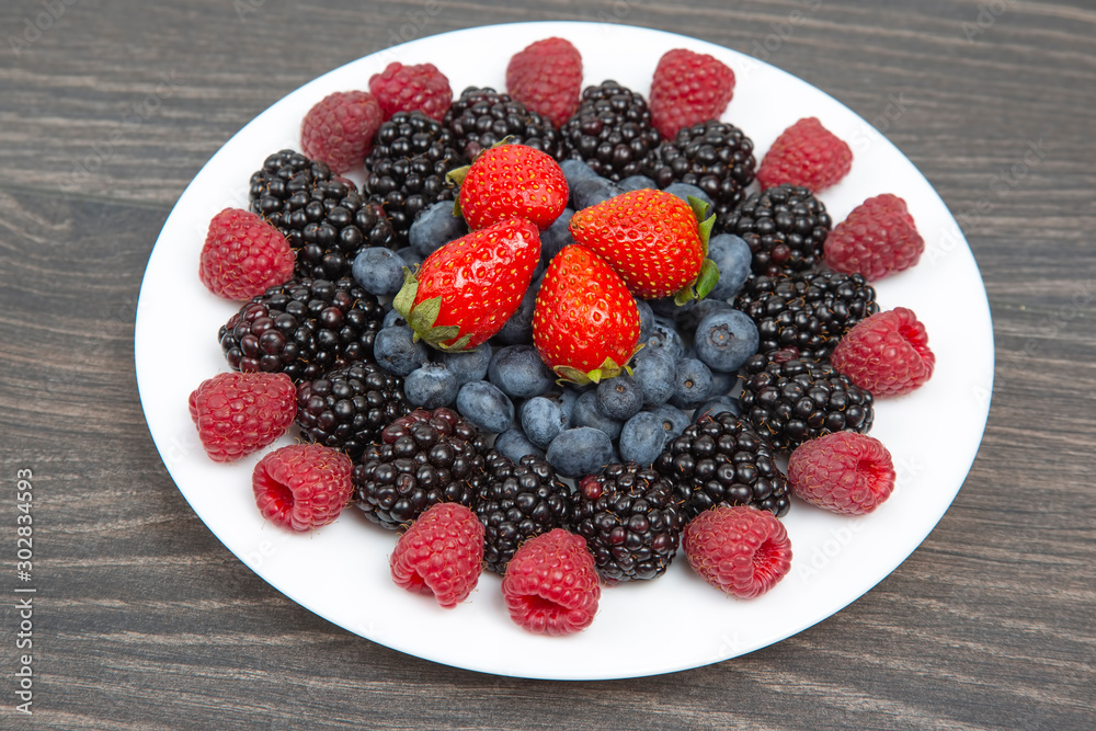 Blackberry, raspberry blueberry and strawberry on a white plate. Vitamins and wholesome foods Blackberry, raspberry blueberry and strawberry on a white plate. Vitamins and wholesome foods