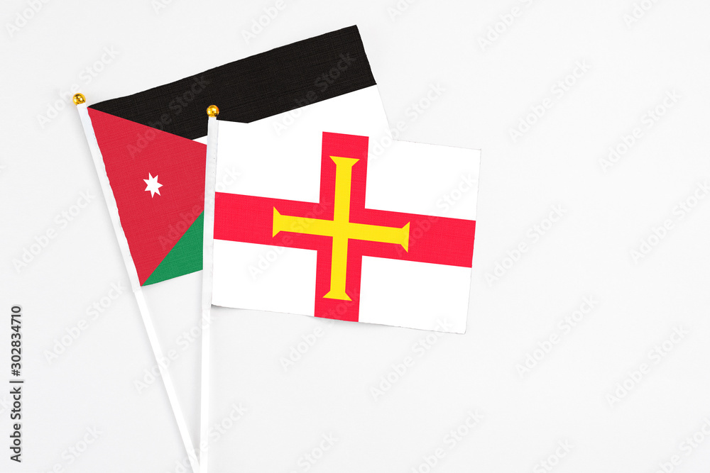 Guernsey and Jordan stick flags on white background. High quality fabric, miniature national flag. Peaceful global concept.White floor for copy space.