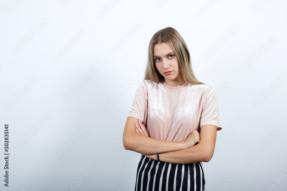 Smiling young woman in casual clothes holding hands crossed, isolated on white wall background. People sincere emotions, lifestyle concept.