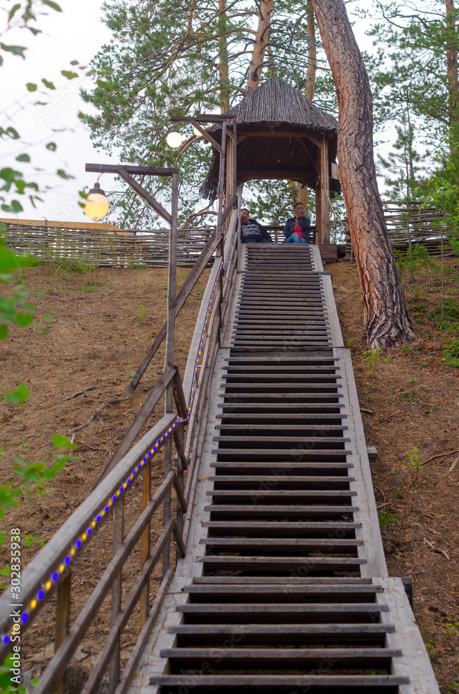 Two Yakut Asian girls sit in a wooden gazebo at the top of a staircase climb with a lantern in the afternoon. Two Yakut Asian girls sit in a wooden gazebo at the top of a staircase climb with a lantern in the afternoon.