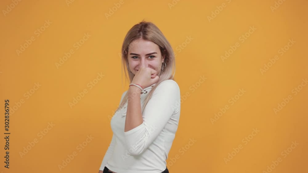 Young caucasian lady wearing pastel white shirt looking so funny, over orange wall happy and pointing to the side Young caucasian lady wearing pastel white shirt looking so funny, over orange wall happy and pointing to the side