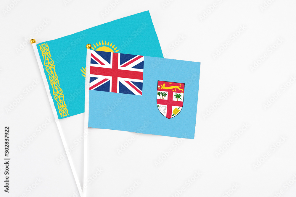 Fototapeta premium Fiji and Kazakhstan stick flags on white background. High quality fabric, miniature national flag. Peaceful global concept.White floor for copy space.