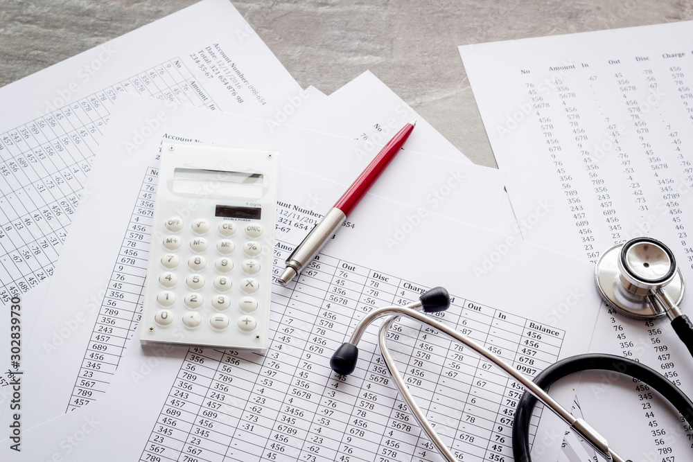 Health insurance concept. Stethoscope near financial documents and calculator on grey background Health insurance concept. Stethoscope near financial documents and calculator on grey background