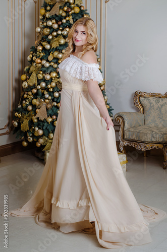 Christmas Couple. New year 2020.Girl with a beige elegant evening dress at the Christmas tree. family holiday at new year studio. lights and sparkles with cheerful woman having fun 