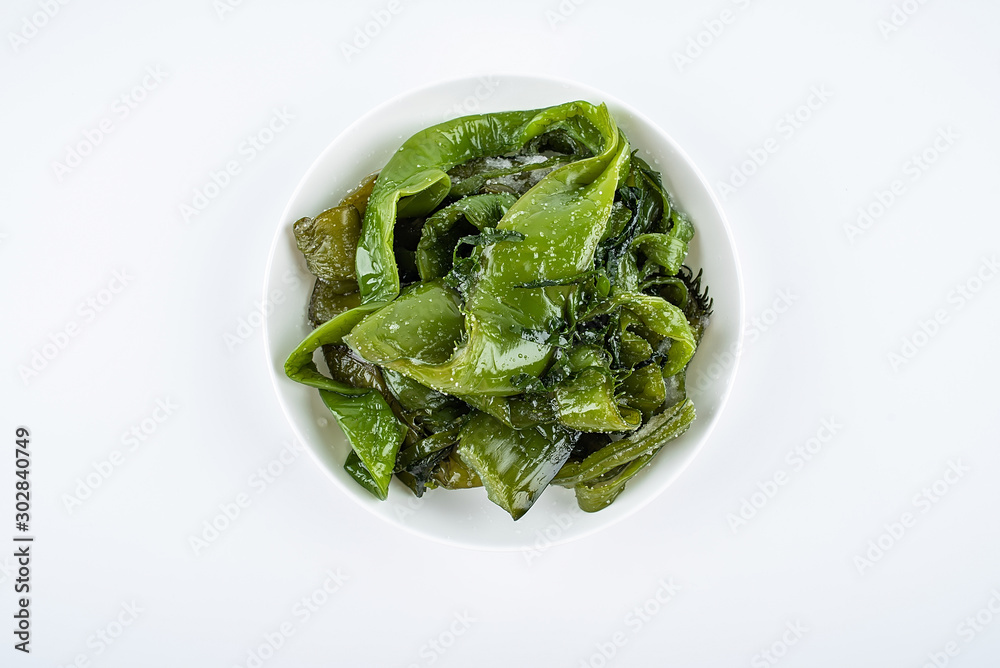 Fresh green salted sea cabbage stems on a saucer on a white background Fresh green salted sea cabbage stems on a saucer on a white background