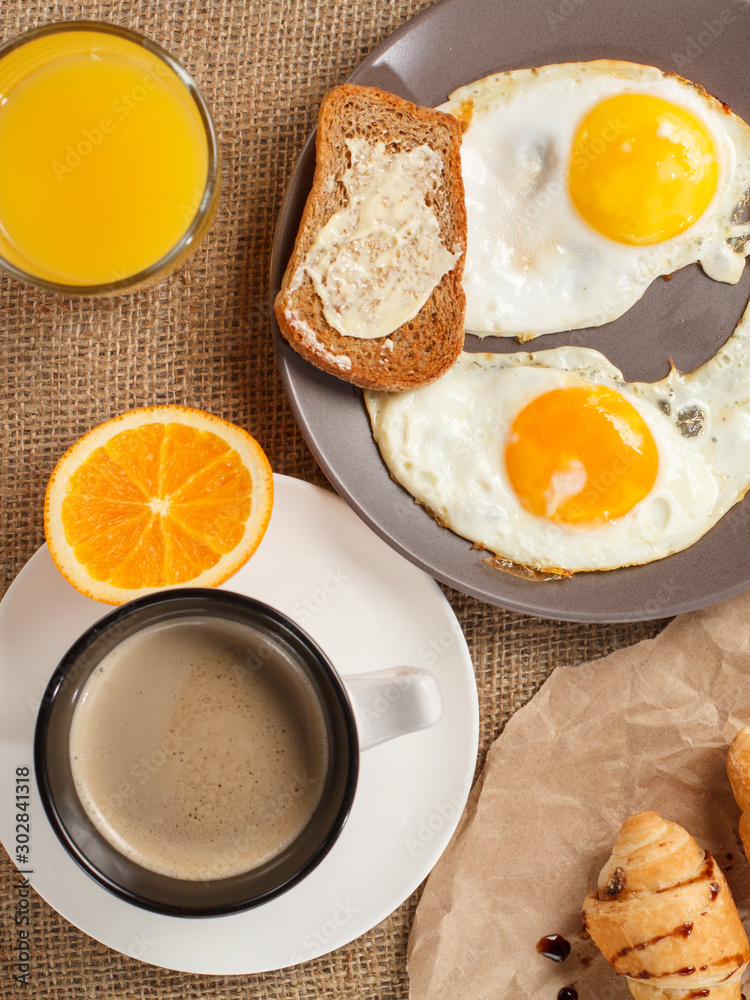Fototapeta premium Plate with fried eggs, glass of orange juice and cup of black coffee