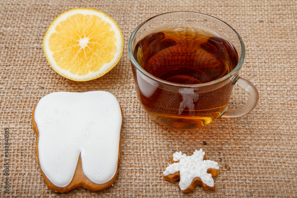 Cup of tea, piece of lemon and gingerbread cookies on sackcloth background.